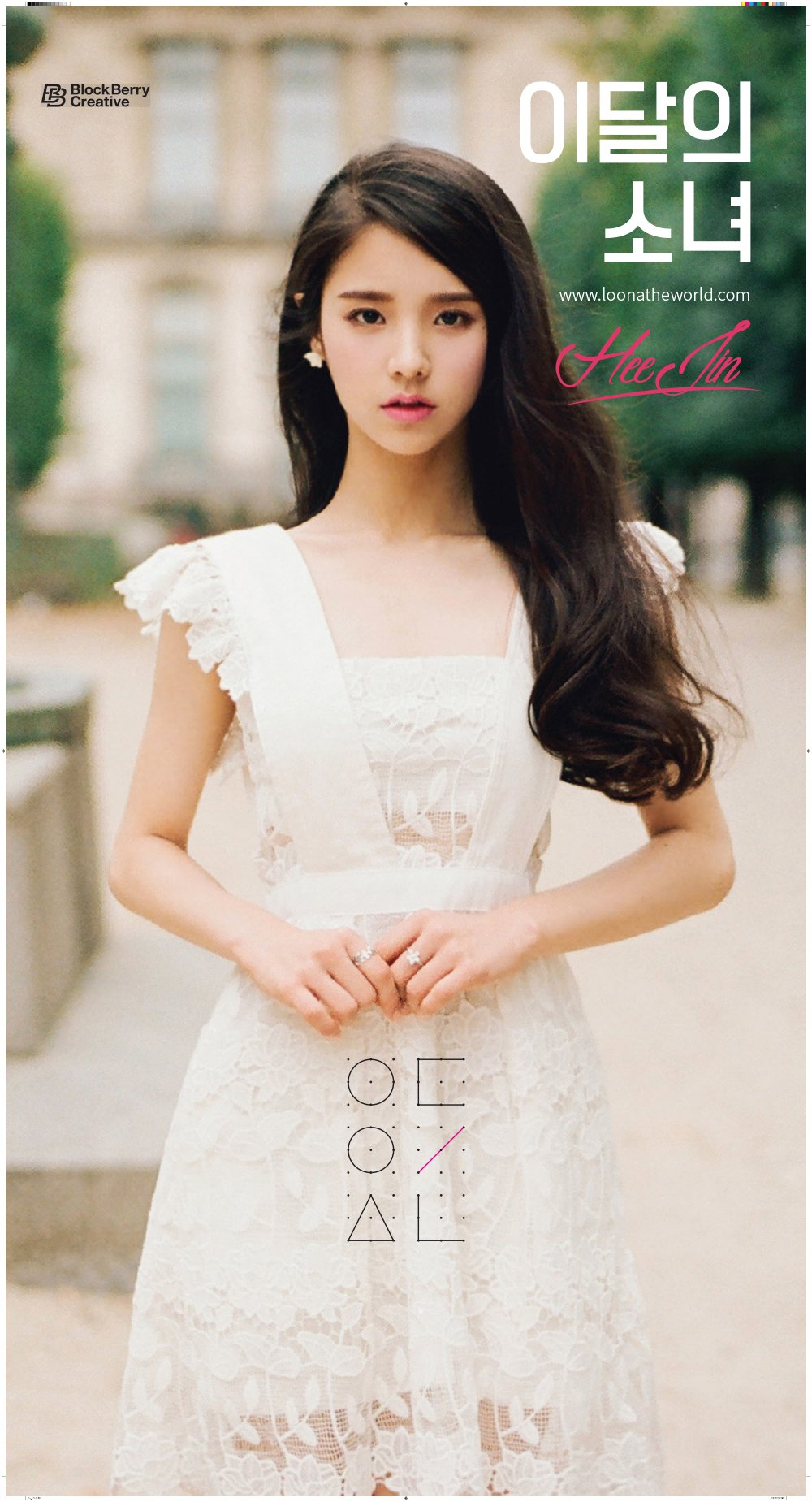 An image of Heejin. She is wearing a fancy dress. Her hands are held in front of her stomach. She is looking at the viewer with a focused, almost blank expression.