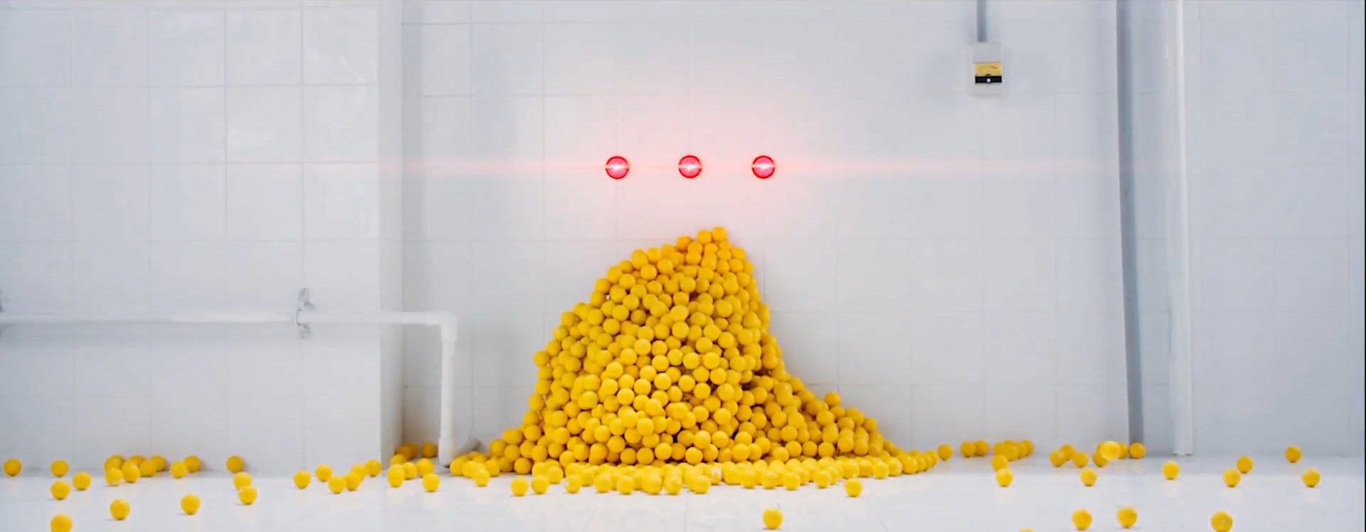 A screenshot of the yellow golf ball pile. The three blue lights on the wall are now glowing bright red, and Heejin is no longer present.