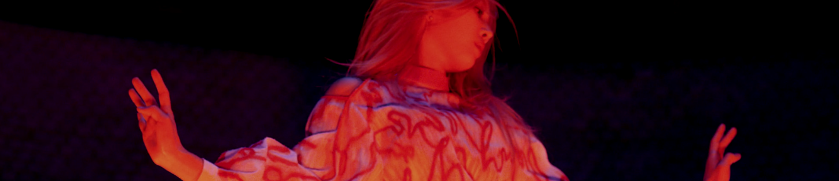 A cropped screenshot from the Eclipse music video. Kim Lip is standing in a black void with her arms out. Her head is tilted to the right, looking away from the viewer. She has long blonde hair and is wearing a red and white patterned shirt.