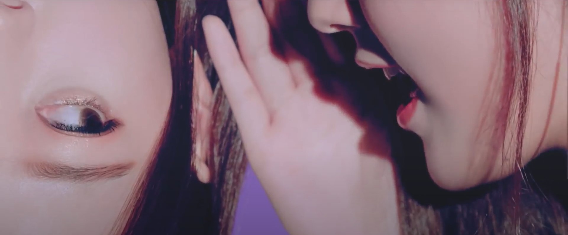 Choerry whispering in the other Choerry's ear, from the Girl Front music video. Both Choerrys have long dark brown hair. The one on the left is upside down, looking over at the other one. The one on the right's eyes aren't visible. She has her hand in front of her with her mouth open. The background is purple.