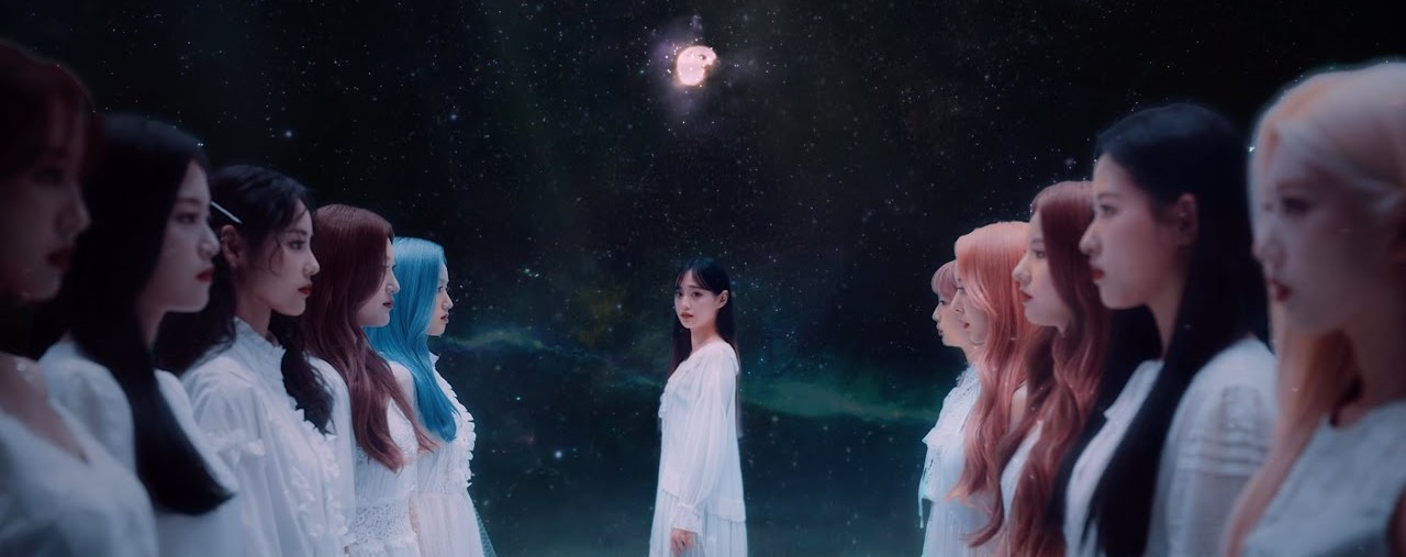 All of the members, minus Haseul, from the Star music video. There are five lined up on each side, with Chuu in the middle. On the left from front to back is Yves, Hyunjin, Jinsoul, Choerry, and Go Won. On the right from front to back is Kim Lip, Olivia Hye, Heejin, Vivi, and Yeojin. They are all wearing white dresses and standing in front of a starry background, with stoic faces.