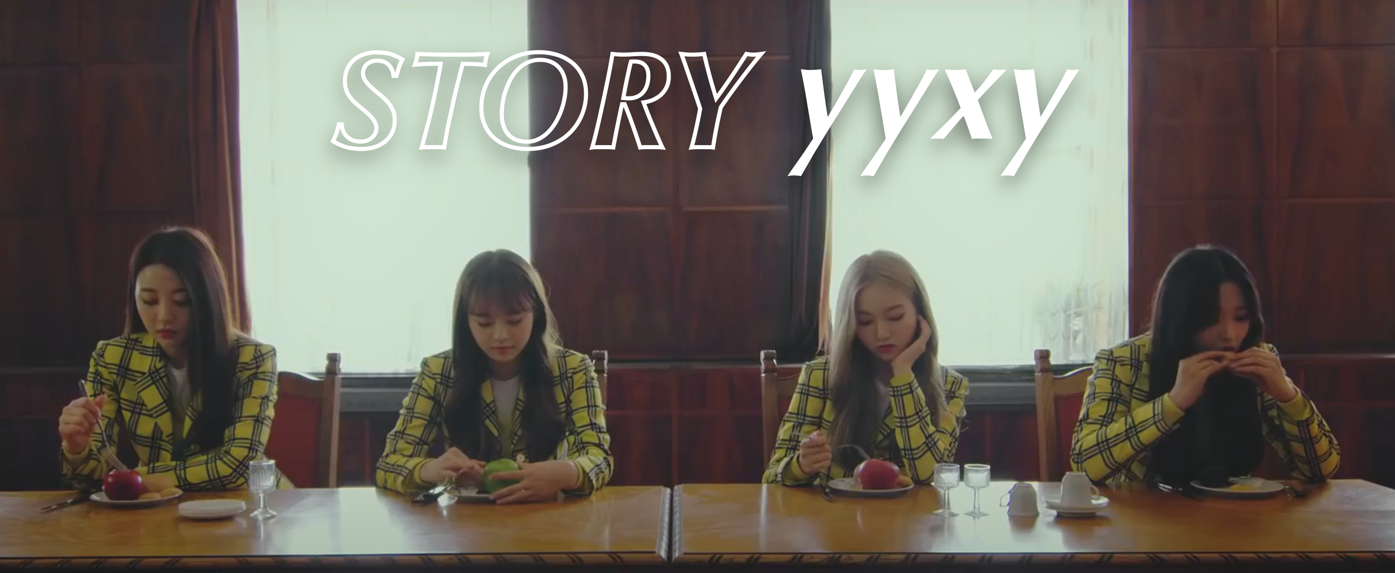 A screenshot from the love4eva music video. The members of yyxy are sat at a table eating. From left to right: Yves, Chuu, Go Won, Olivia Hye. They are all wearing their yellow plaid uniforms. Yves has long black hair and is picking at the red apple on her plate with a fork. Chuu has long light brown hair and is running her hands over the green apple on her plate. Go Won has long blonde hair and is also picking at the red apple on her plate with a fork. Olivia has long black hair and does not have an apple on her plate. She instead has a regular plate of food, some of which she is biting into with both hands. They are sat in front of two large white windows. Large white text has been placed over the image, reading 'STORY yyxy.'